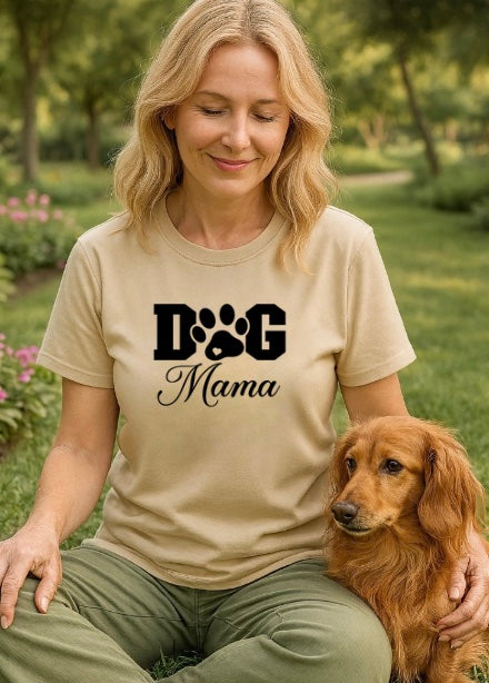 Woman wearing a 'Dog Mama' t-shirt sitting with a dog in a park.