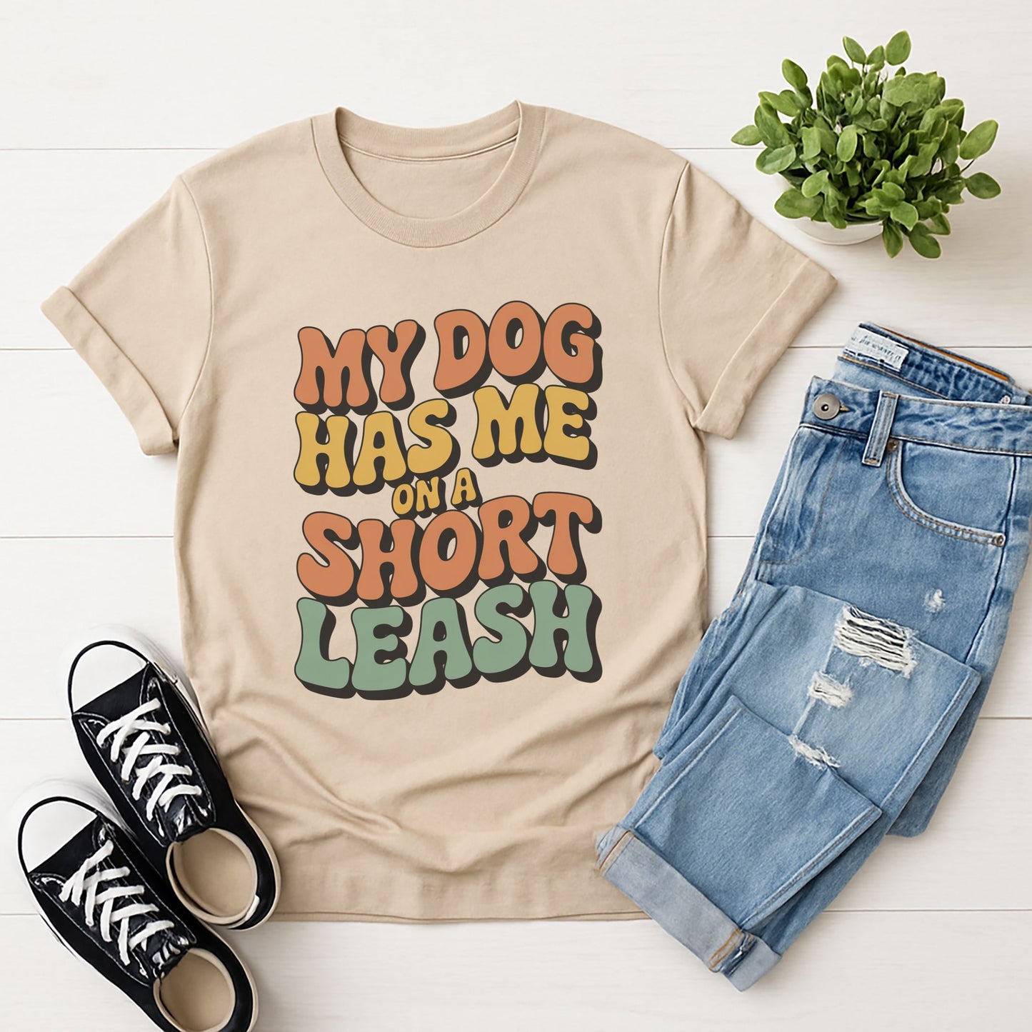 Sand Beige Gildan 6400 unisex t-shirt with retro dog graphic and ‘My Dog Has Me On A Short Leash’ text, perfect for dog lovers.