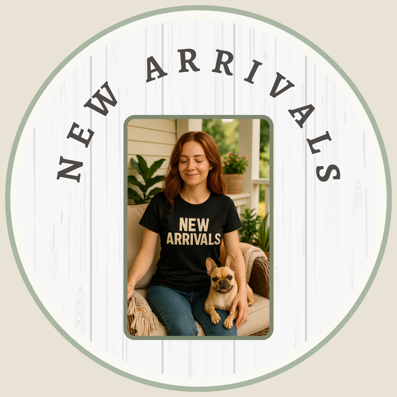 A happy woman with long auburn hair sits on a porch wearing a black t-shirt that says "NEW ARRIVALS" with her dog beside her.