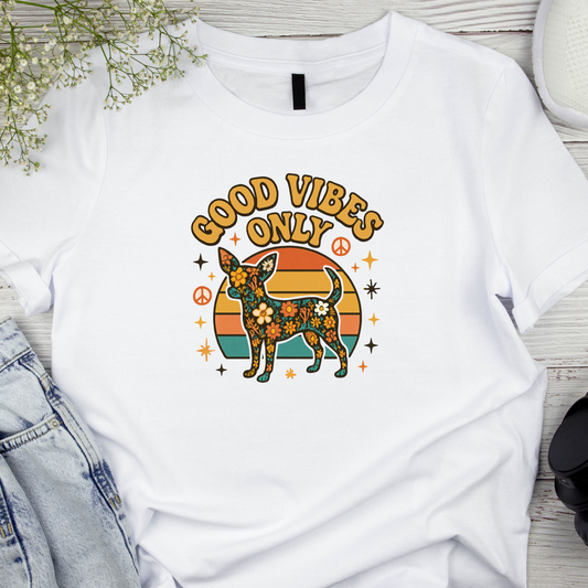 White t-shirt with a dog graphic and 'Good Vibes Only' text on a wooden surface.