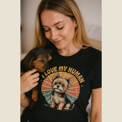Woman wearing a black t-shirt with a dog graphic and 'I love my human' text, holding a small dog.