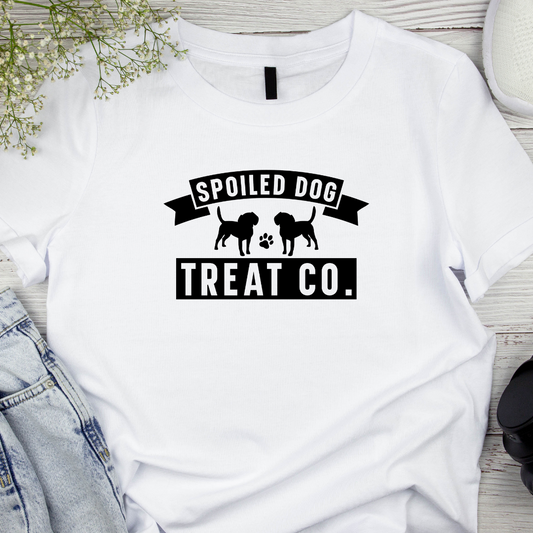 White t-shirt with 'Spoiled Dog Treat Co.' text and graphics on a wooden surface.