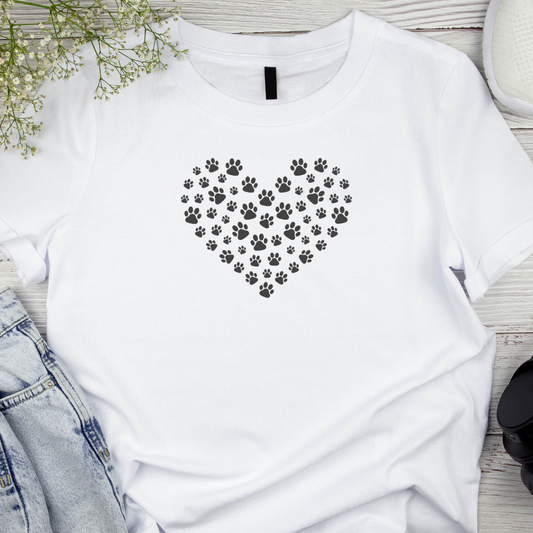 White t-shirt with a heart design made of paw prints on a wooden surface.