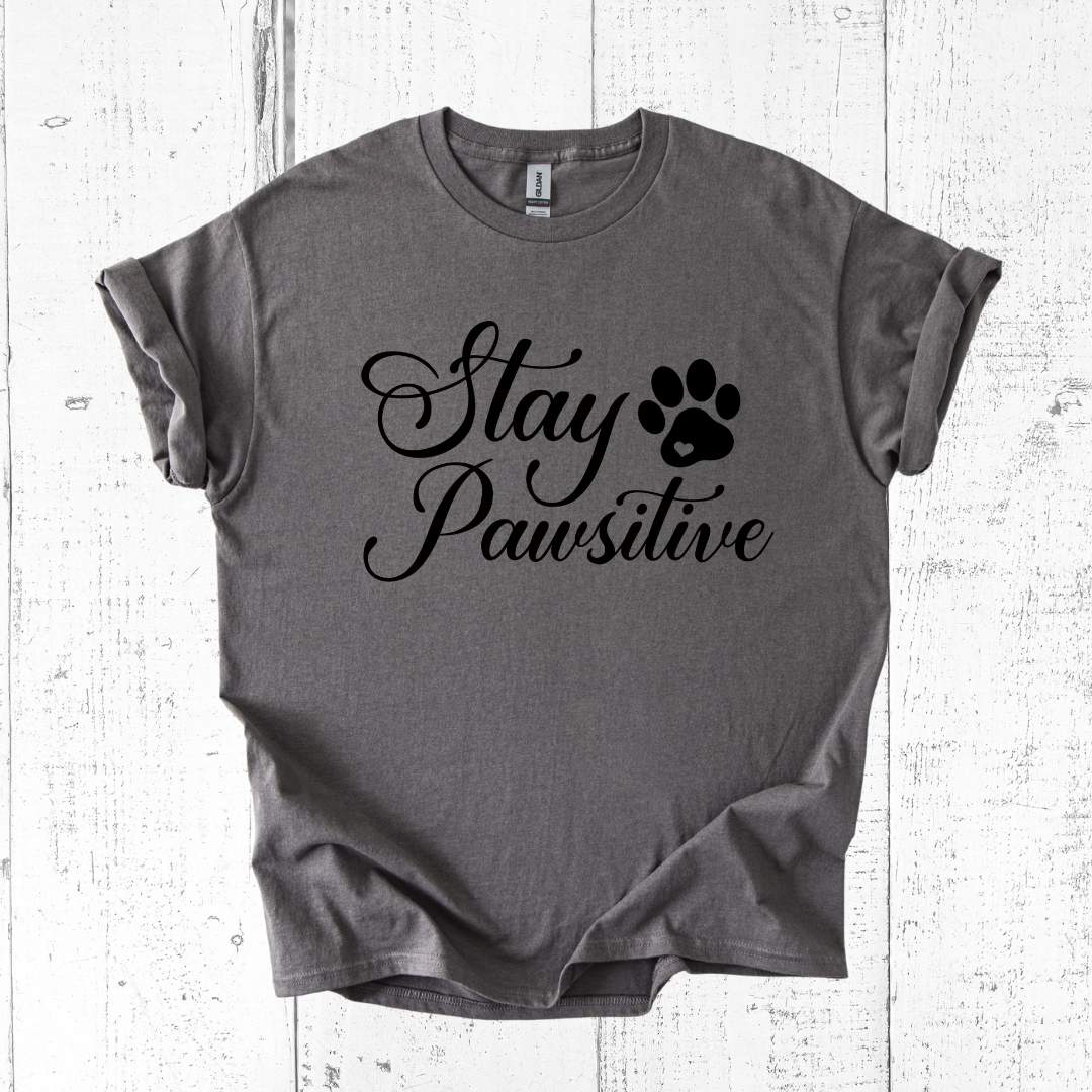 Gray t-shirt with 'Stay Pawsitive' text and paw print on a white wooden background