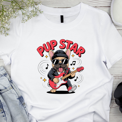 White t-shirt with a cartoon dog playing guitar and text 'Pup Star' on a wooden surface.