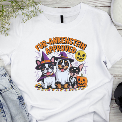 White t-shirt with Halloween-themed design featuring dogs in costumes on a wooden surface.