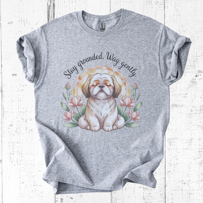 Gray t-shirt with a dog graphic and text 'Stay grounded, Wag gently' on a wooden surface.