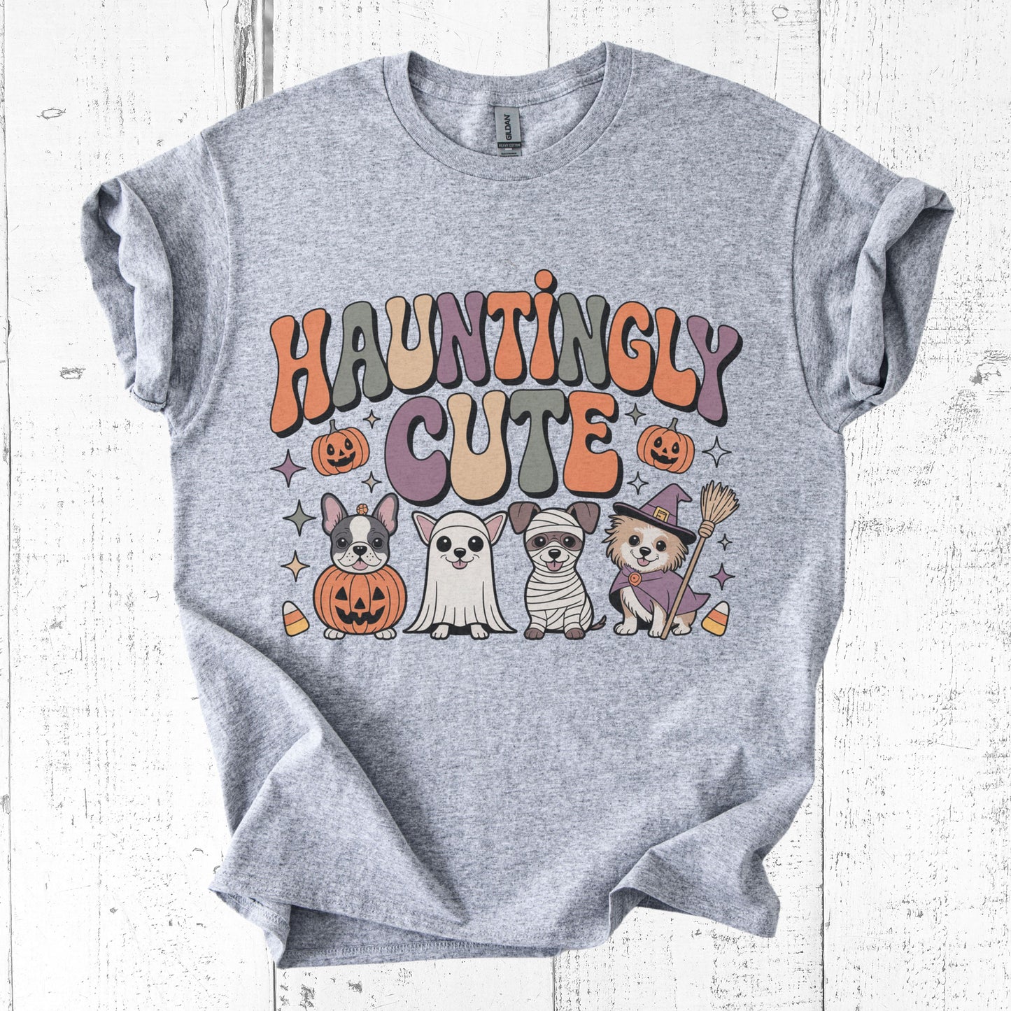Gray t-shirt with 'Hauntingly Cute' text and Halloween-themed graphics on a white wooden background