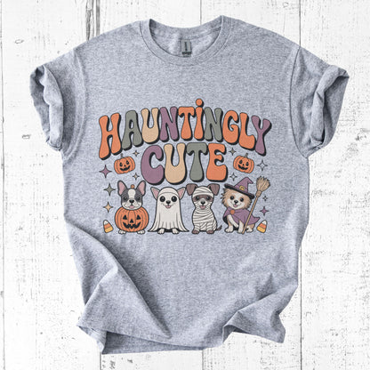 Gray t-shirt with 'Hauntingly Cute' text and Halloween-themed graphics on a white wooden background