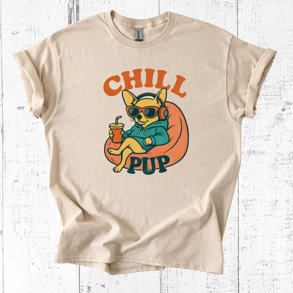 Beige t-shirt with a graphic of a dog wearing sunglasses and headphones, holding a drink, with 'Chill Pup' text on a white wooden background.