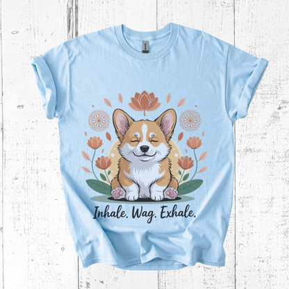 Light blue t-shirt with a corgi graphic and 'Inhale. Wag. Exhale.' text on a wooden surface.