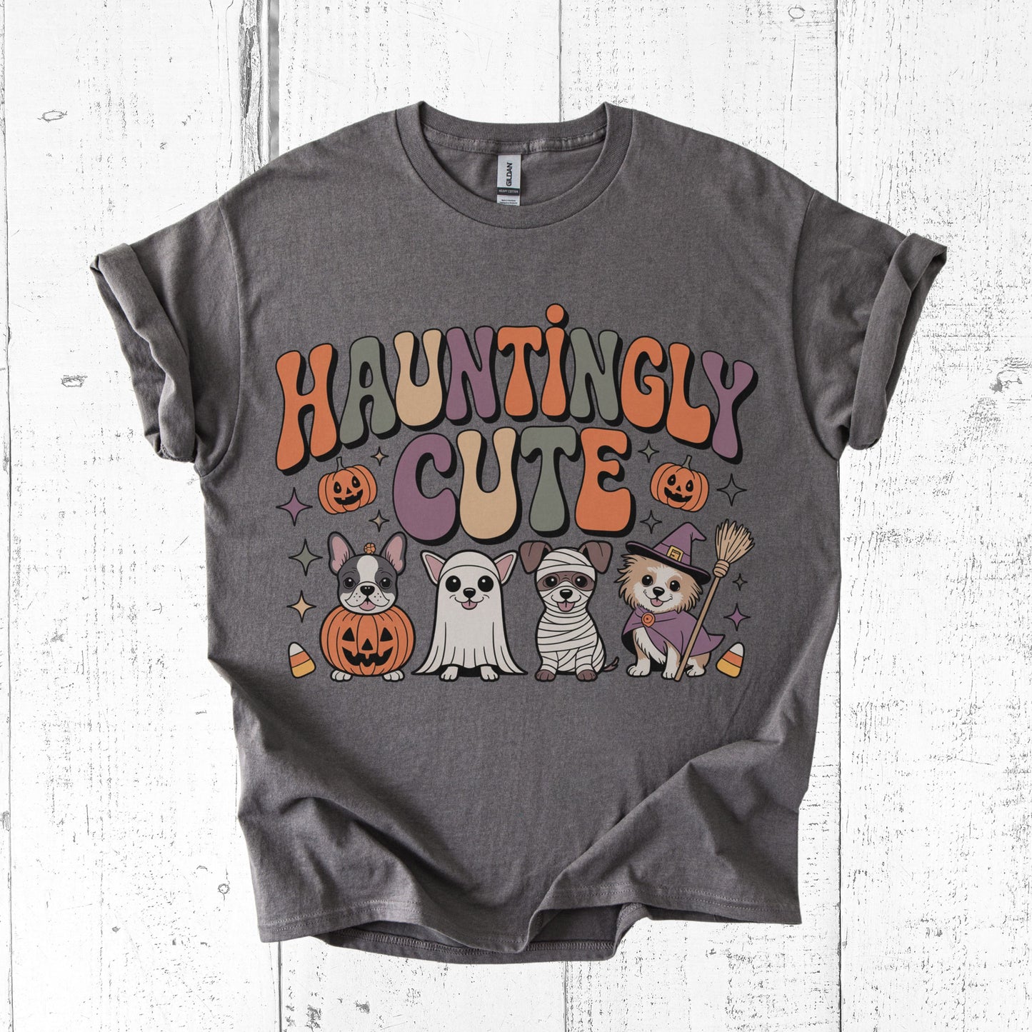 Gray t-shirt with Halloween-themed graphics and 'Hauntingly Cute' text on a white wooden background