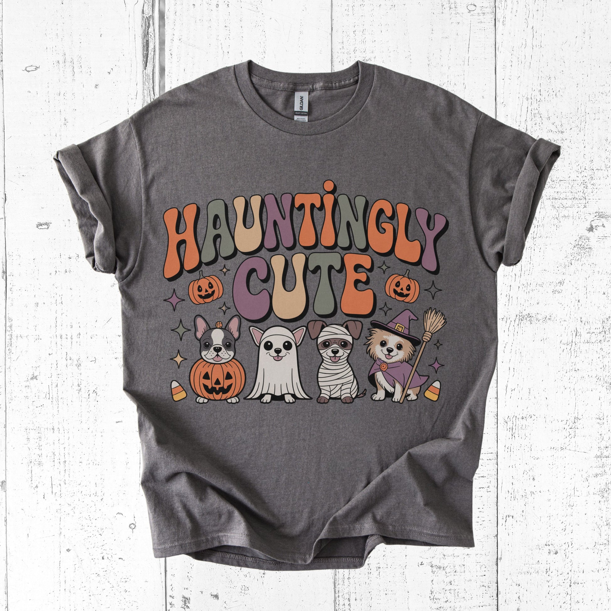 Gray t-shirt with Halloween-themed graphics and 'Hauntingly Cute' text on a white wooden background