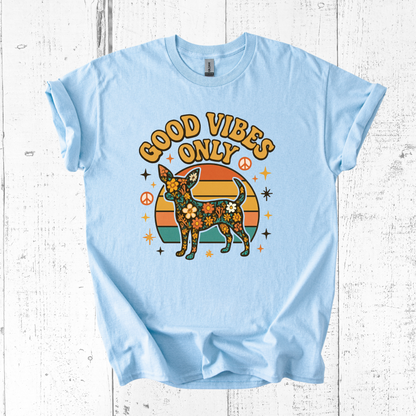 Light blue t-shirt with a graphic of a dog and 'Good Vibes Only' text on a wooden surface