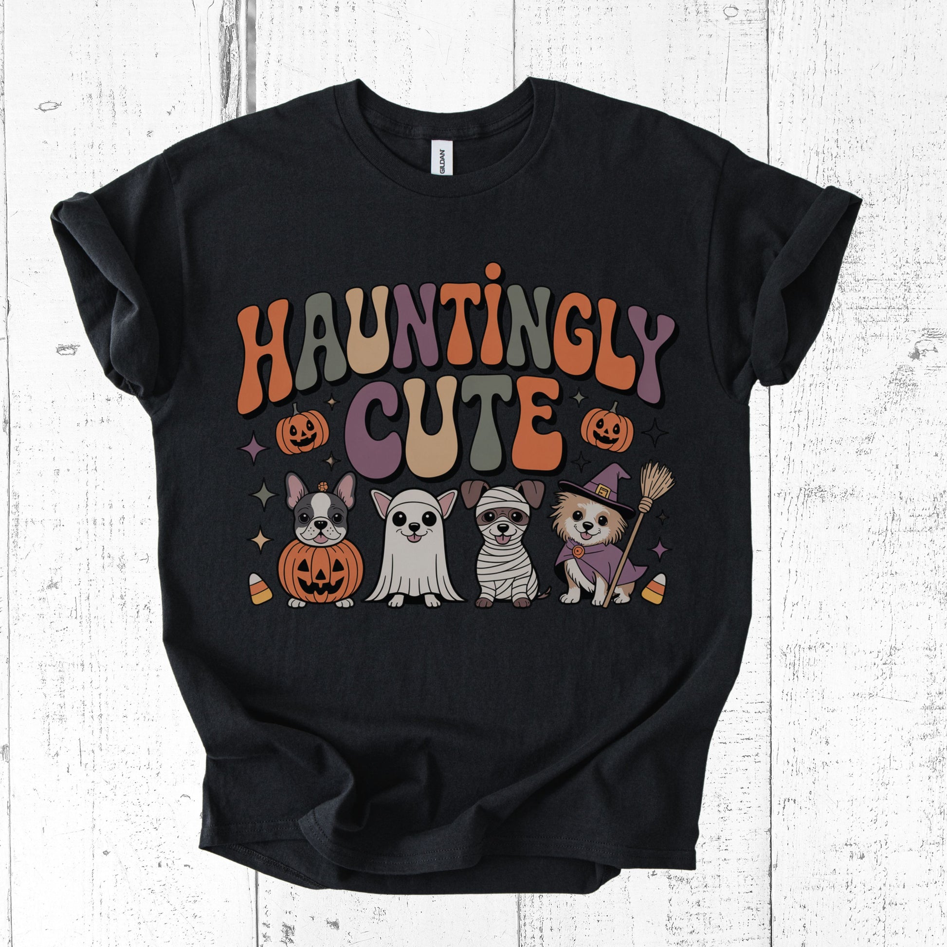 Black t-shirt with 'Hauntingly Cute' text and Halloween-themed graphics on a white wooden background