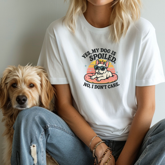 Person wearing a white t-shirt with a dog graphic and text, sitting next to a dog.
