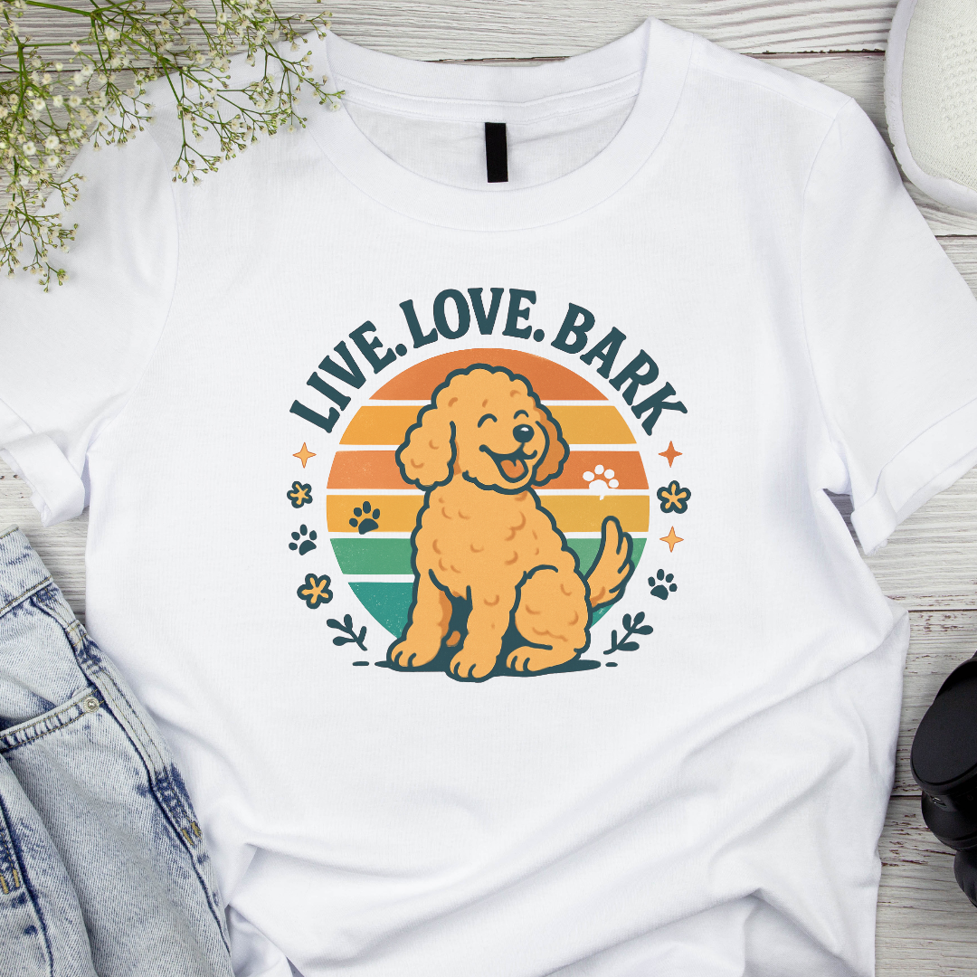 White t-shirt with a dog graphic and 'Live. Love. Bark' text on a wooden surface.