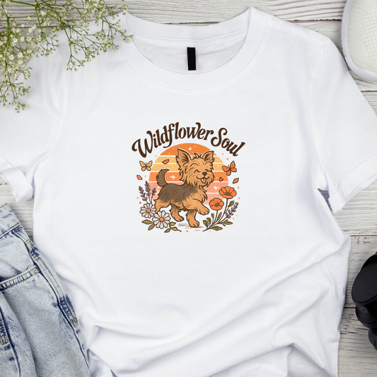 White t-shirt with a dog graphic and 'Wildflower Soul' text on a wooden surface.