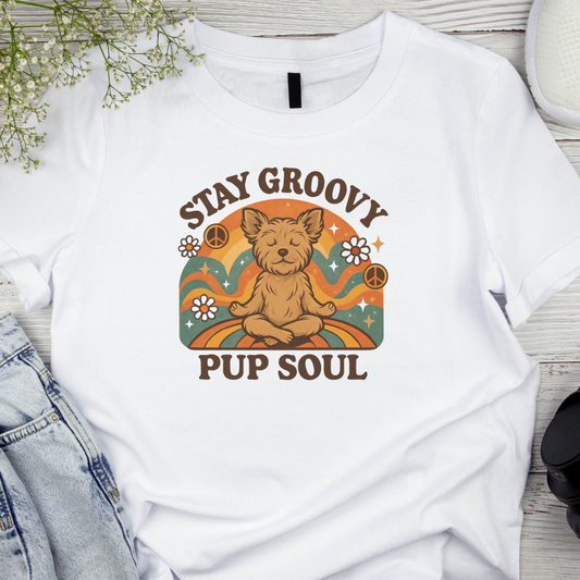 White t-shirt with a graphic of a dog and text 'Stay Groovy Pup Soul' on a wooden surface.