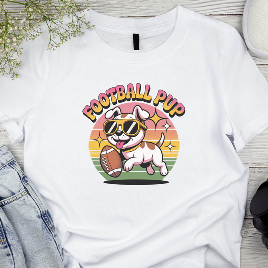 White t-shirt with 'Football Pup' graphic design featuring a dog with sunglasses and a football, on a wooden surface.