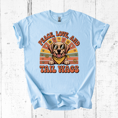 Light blue t-shirt with a dog graphic and text 'Peace, Love, and Tail Wags' on a wooden surface.