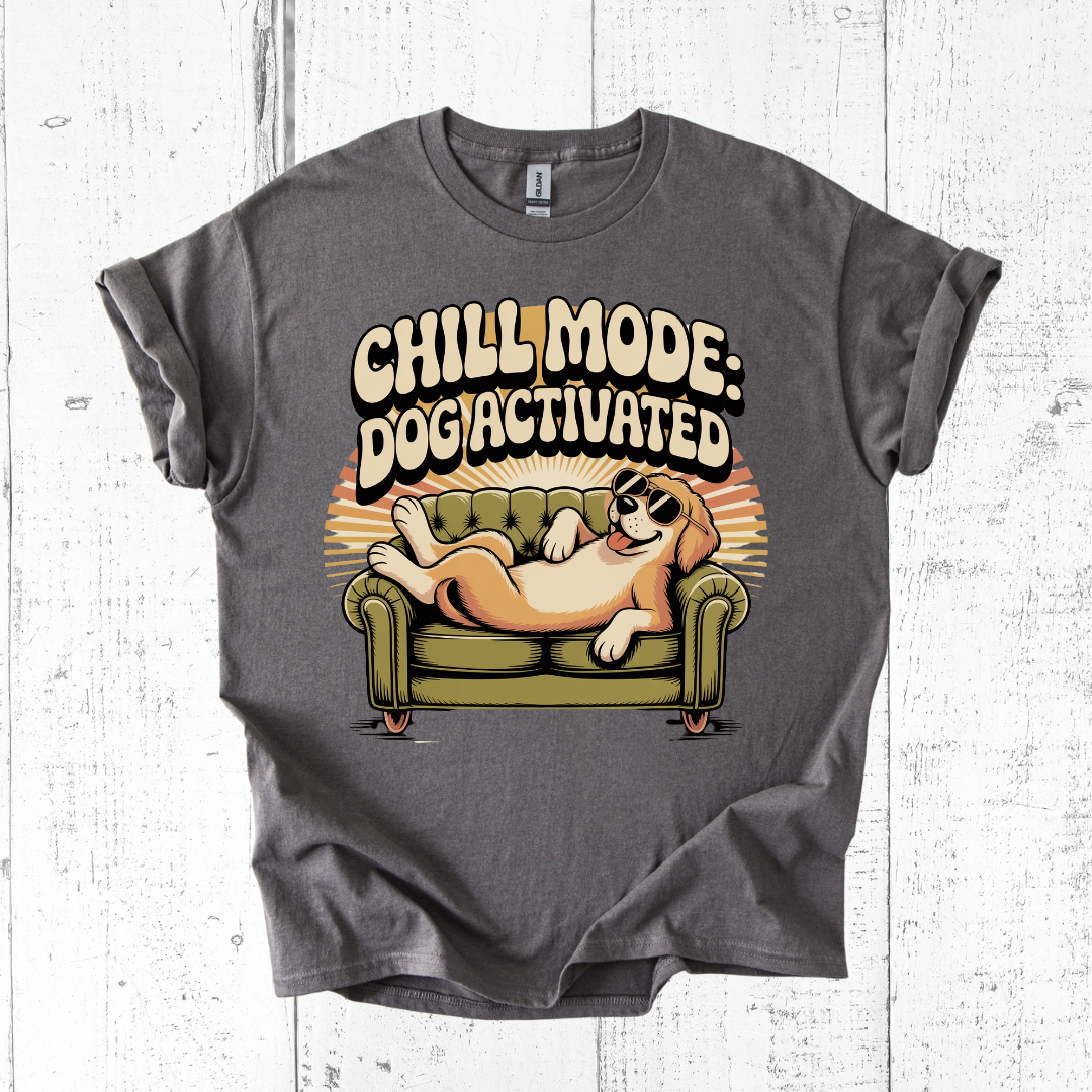 Gray t-shirt with a graphic of a dog on a couch and text 'Chill Mode: Dogi Activated' on a white wooden background.