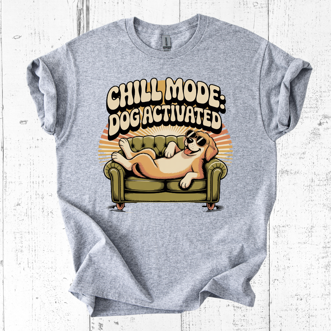 Gray t-shirt with a graphic of a dog on a couch and text 'Chill Mode: Dogi Activated' on a white wooden background.