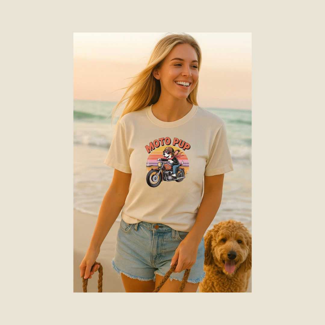 Woman on a beach wearing a 'Moto Pup' t-shirt with a dog graphic, standing next to a dog.
