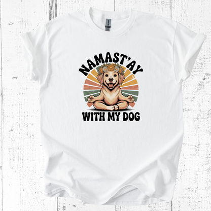 White t-shirt with a graphic of a dog sitting in a meditative pose and text 'Namast'ay with my dog' on a wooden surface.