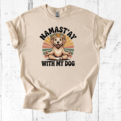 Beige t-shirt with a graphic of a dog and text 'Namast'ay with my dog' on a white wooden background
