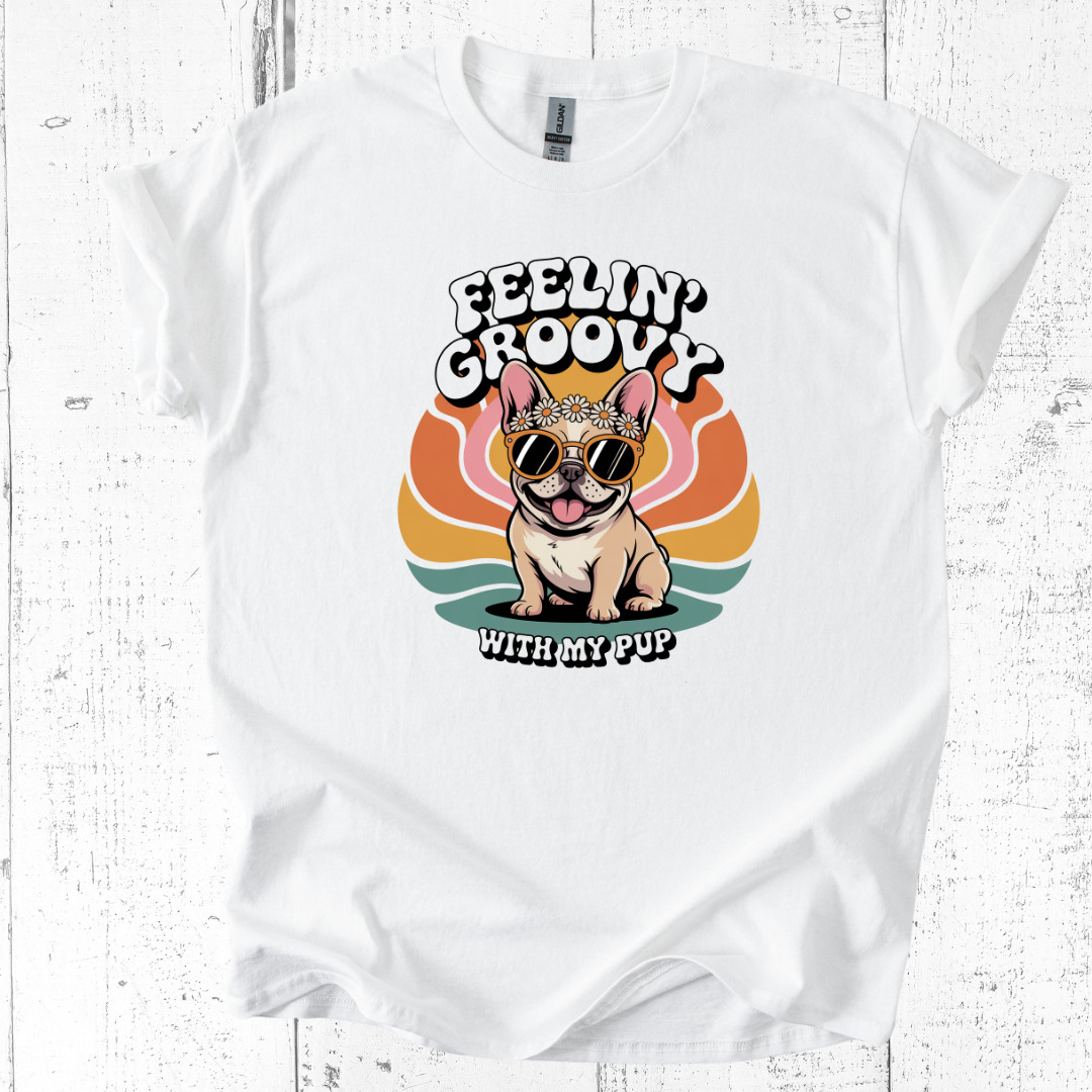 White t-shirt with a dog graphic and 'Feelin' Groovy with my pup' text on a wooden surface