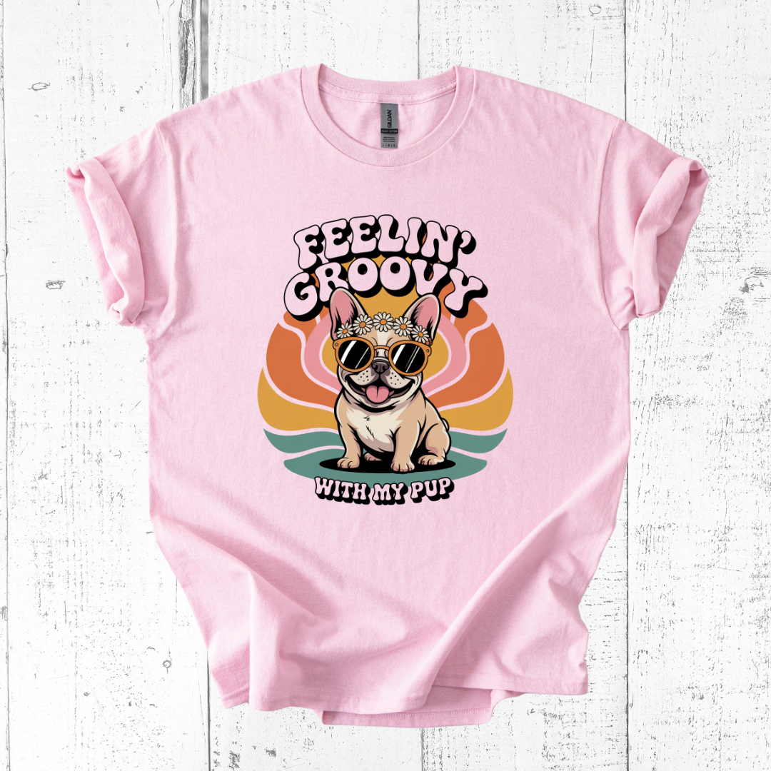 Pink t-shirt with a dog graphic and 'Feelin' Groovy with my Pup' text on a white wooden background