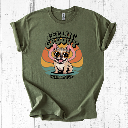 Green t-shirt with a dog graphic and 'Feelin' Groovy with my pup' text on a white wooden background