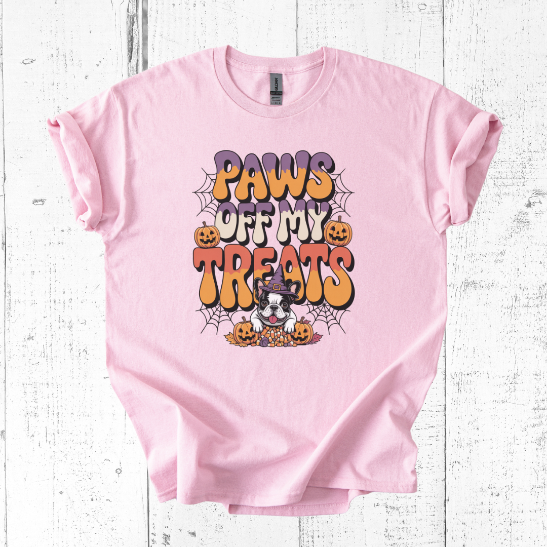 Pink t-shirt with Halloween-themed text and graphics on a white wooden background