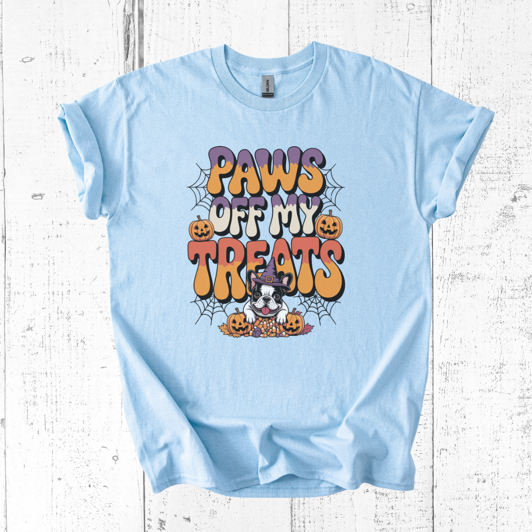 Light blue t-shirt with Halloween-themed design and text 'Paws Off My Treats' on a wooden surface.