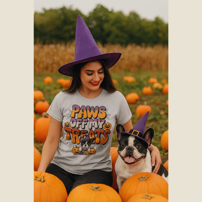 Woman wearing a Halloween-themed shirt and purple witch hat with a dog in a pumpkin patch.
