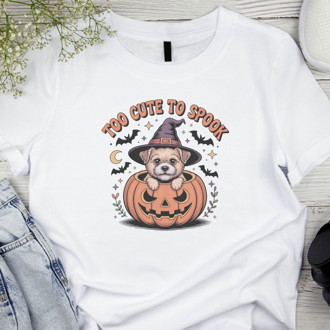 White t-shirt with a Halloween-themed design featuring a dog in a pumpkin and text 'Too Cute to Spook'.
