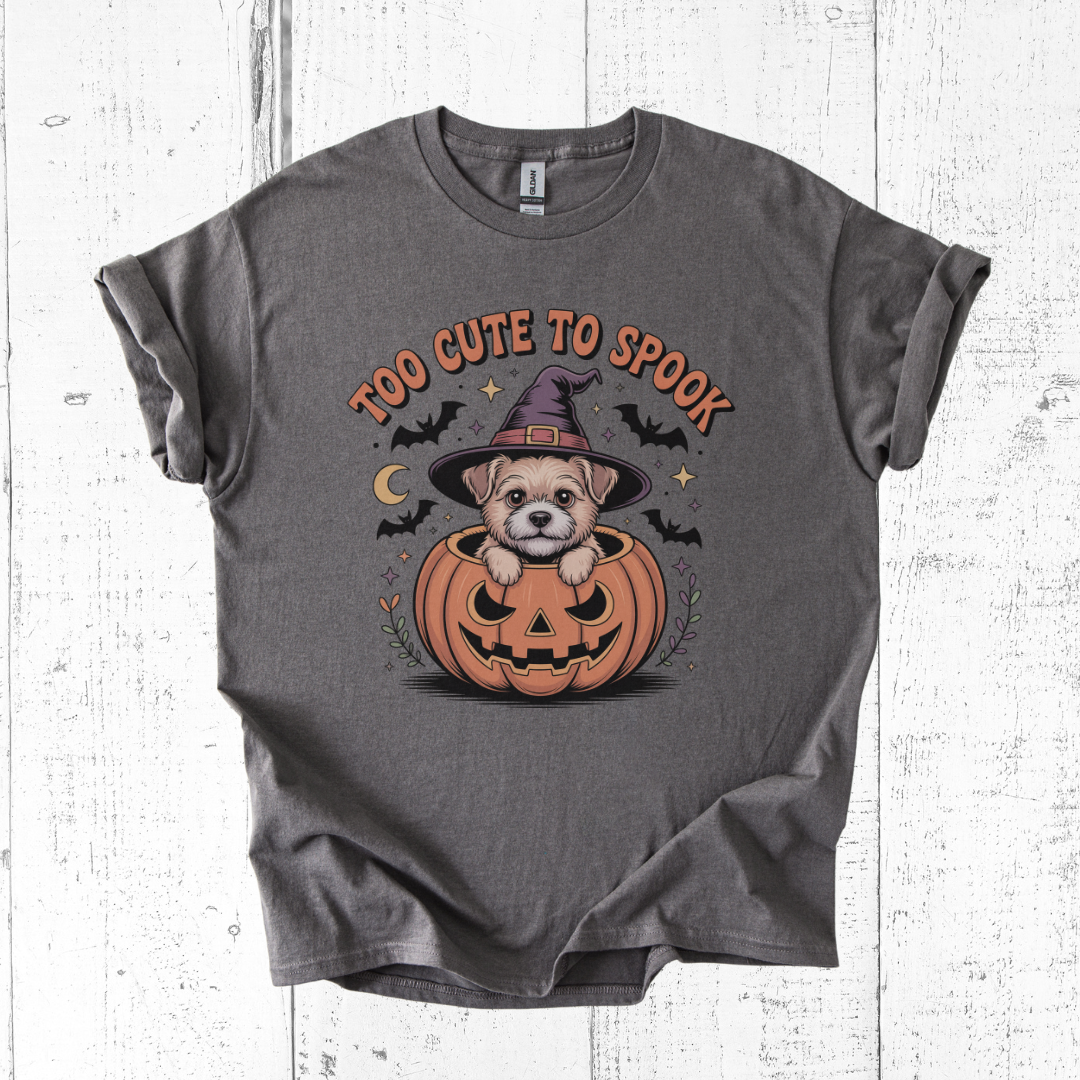 Gray t-shirt with Halloween design of a dog in a pumpkin and text 'Too Cute to Spook' on a wooden surface.