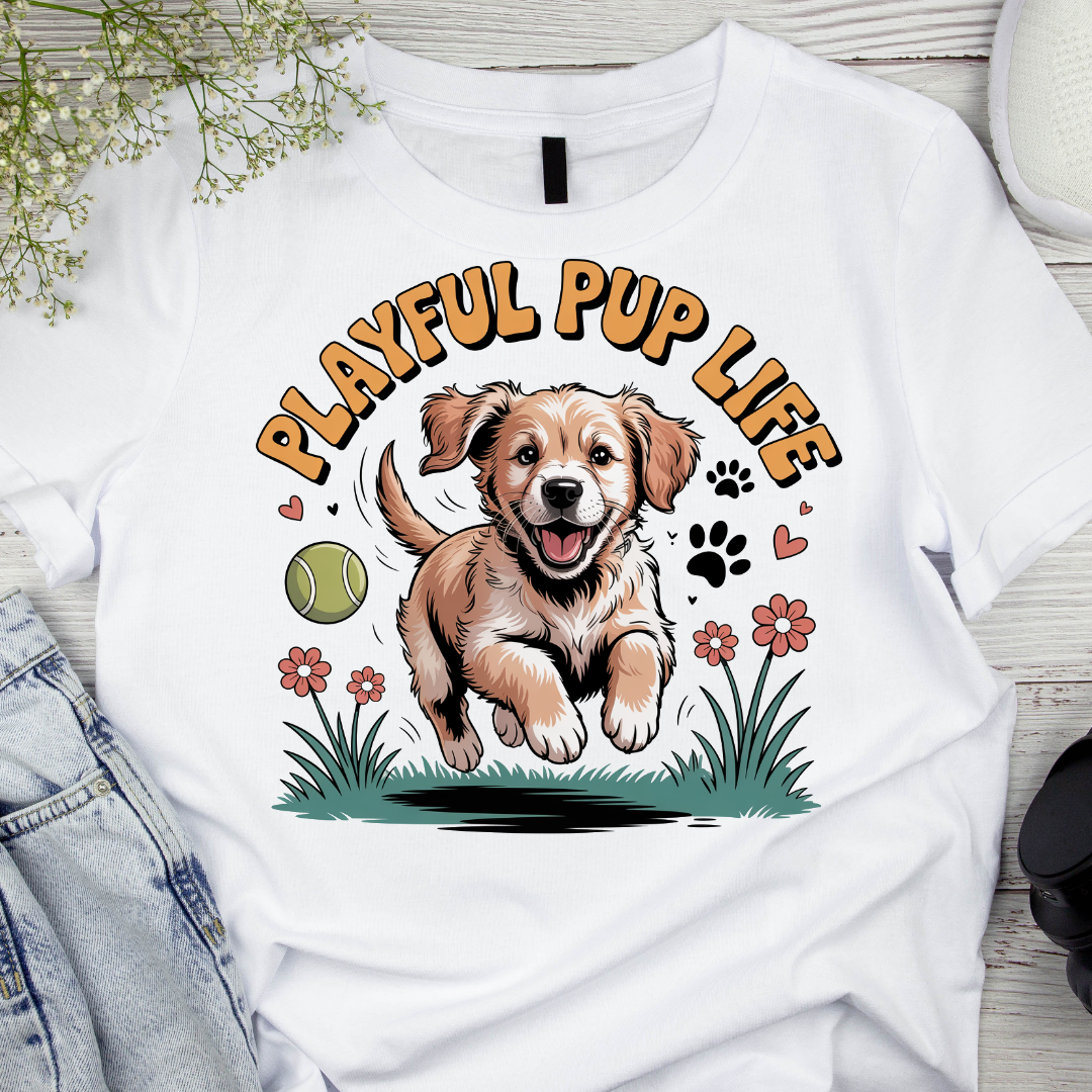 White t-shirt with a graphic of a puppy and 'Playful Pup Life' text on a wooden surface.
