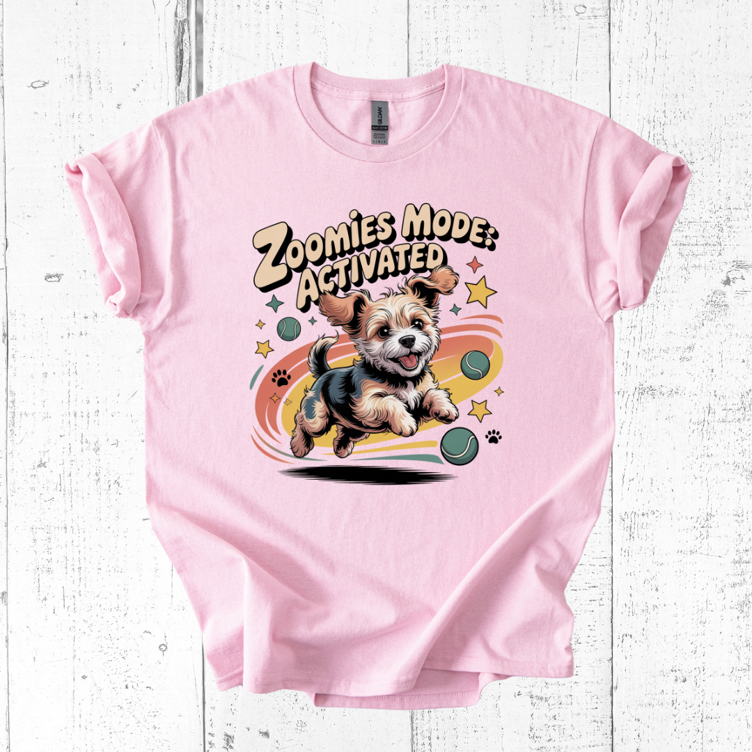Pink t-shirt with a dog graphic and 'Zoomies Mode Activated' text on a wooden surface