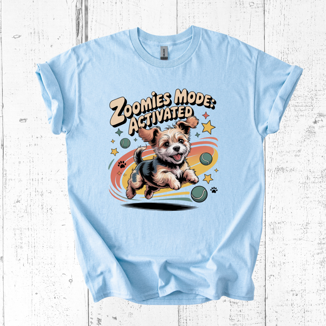 Light blue t-shirt with a dog graphic and 'Zoomies Mode Activated' text on a wooden surface.
