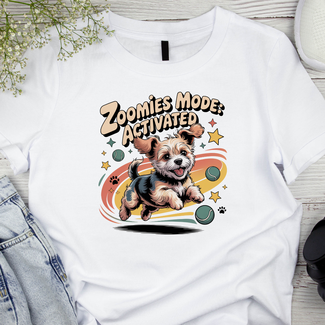 White t-shirt with a dog graphic and 'Zoomies Mode Activated' text on a wooden surface.