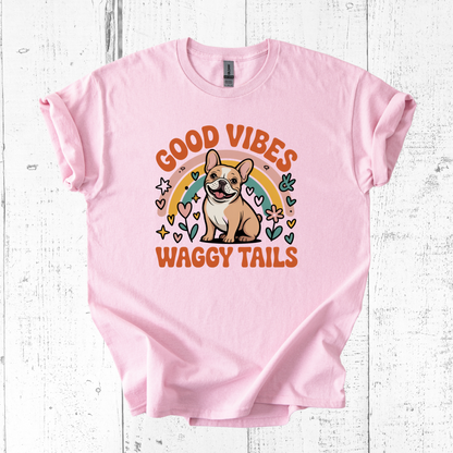 Pink t-shirt with a dog graphic and 'Good Vibes Waggy Tails' text on a white wooden background