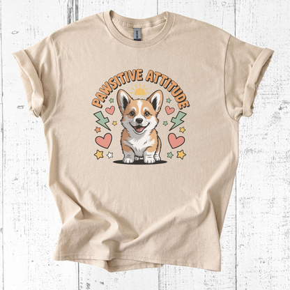 Beige t-shirt with a corgi graphic and 'Pawsitive Attitude' text on a white wooden background