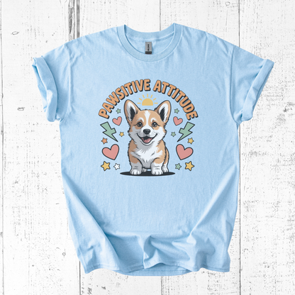Light blue t-shirt with a corgi graphic and 'Pawsititive Attitude' text on a wooden surface