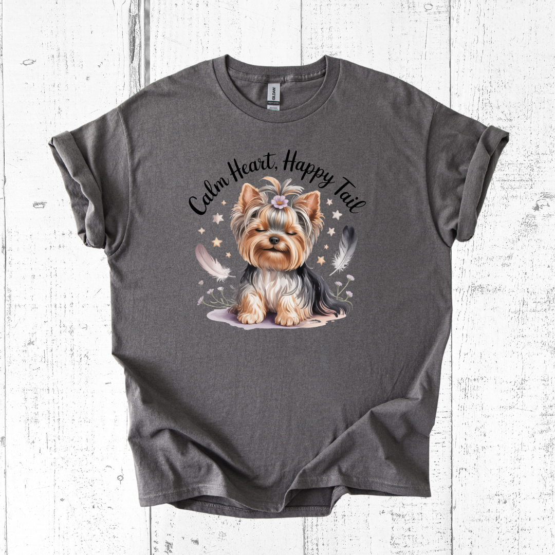 Gray t-shirt with a dog illustration and 'Calm Heart, Happy Tail' text on a wooden surface