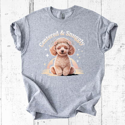 Gray t-shirt with a graphic of a dog and text 'Cuddled & Snuggly' on a wooden surface.