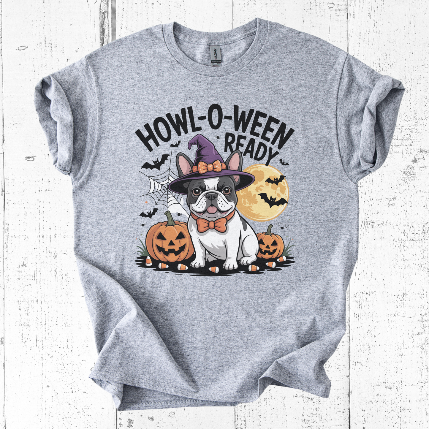 Gray t-shirt with a Halloween-themed design featuring a dog in a witch hat and pumpkins on a white wooden background.
