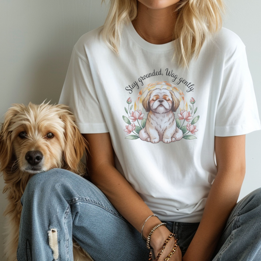 Person wearing a white t-shirt with a dog graphic and text, sitting next to a dog.