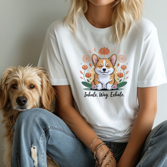 Person wearing a white t-shirt with a corgi graphic and text, sitting next to a dog.